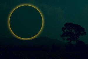 anello eclisse luna indietro silhouette albero e montagna nel cielo notturno foto