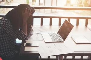 mani di donna frustrate mentre è seduto al suo posto di lavoro in ufficio. foto