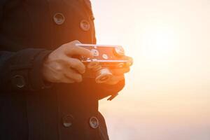 mani di donna che tengono la fotocamera retrò con il cappotto nero foto