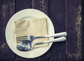 annata di cucchiaio e forchetta sul piatto bianco foto