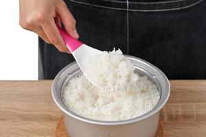 la donna usa il cucchiaio di riso per raccogliere il riso dalla pentola foto