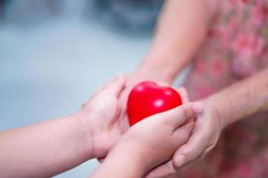 il bambino dà il cuore rosso alla nonna anziana. foto