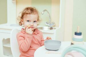 poco bambino mangia pasta nel il figli di cucina foto