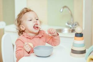 poco bambino mangia pasta nel il figli di cucina foto