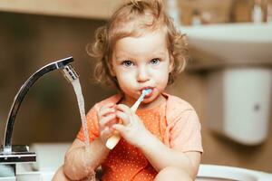 allegro contento bambino spazzole il suo denti nel il mattina nel il bagno foto