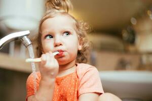 contento bambino spazzolatura il suo denti nel il mattina nel il bagno foto