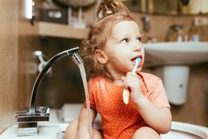 allegro contento bambino spazzole il suo denti nel il mattina nel il bagno foto