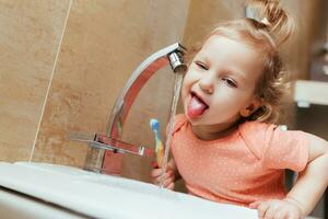 allegro e divertente ragazza spazzolatura sua denti nel il mattina foto