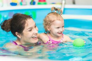 contento madre nuotate nel il piscina con sua figlia foto