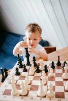 bambino giocando scacchi a casa a il tavolo foto