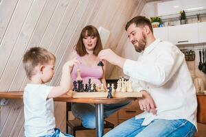 contento famiglia giocando scacchi nel il cucina foto