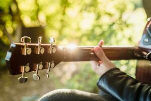 uomo giocando acustico chitarra nel natura su un' soleggiato giorno foto