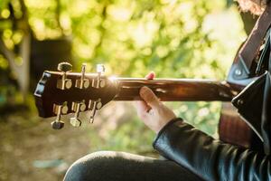 musicista uomo giocando chitarra a tramonto avvicinamento foto