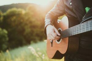 uomo giocando chitarra nel natura su un' soleggiato giorno foto