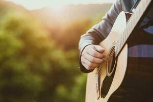 uomo giocando acustico chitarra nel natura su un' soleggiato giorno foto