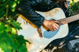 uomo giocando chitarra nel natura su un' soleggiato giorno foto