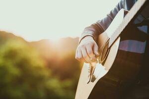 uomo giocando chitarra nel natura su un' soleggiato giorno foto