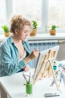 bellissimo ragazza artista vernici su tela a casa foto