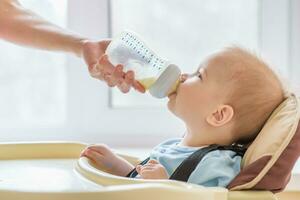 mamma è alimentazione sua bambino un' bottiglia di latte foto