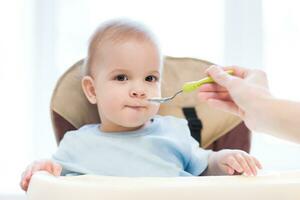 madre dà bambino cibo a partire dal un' cucchiaio foto