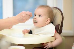 nonna dà bambino cibo a partire dal un' cucchiaio foto