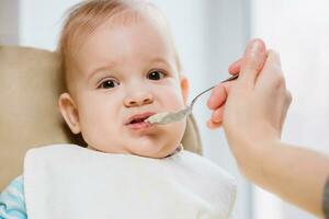 madre dà bambino cibo a partire dal un' cucchiaio foto