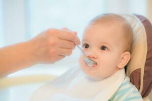 nonna dà bambino cibo a partire dal un' cucchiaio foto