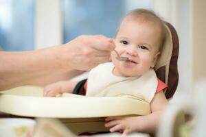 nonna dà bambino cibo a partire dal un' cucchiaio foto