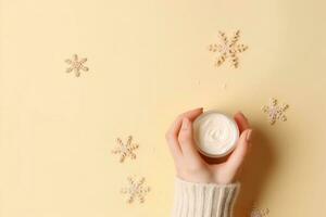 inverno stagione pelle cura cosmetici concetto. primo persona superiore Visualizza foto di donna di mani nel a maglia maglione piccolo crema vaso e i fiocchi di neve su isolato pastello beige sfondo. generativo ai.