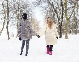 mamma e figlia a piedi nel il neve di il mano foto