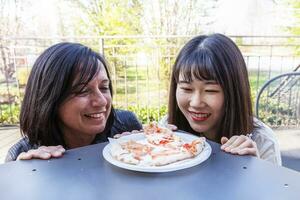 giovane multietnico femmina amici Guardando un' gustoso Pizza foto