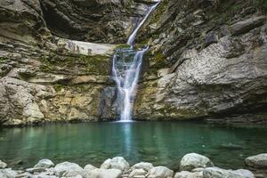 meraviglioso piccolo cascata quello le forme un' stagno di Smeraldo acqua nel un' foresta foto