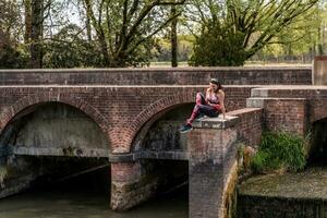bellissimo maturo donna assunzione un' rilassante momento su un' mattone ponte all'aperto foto