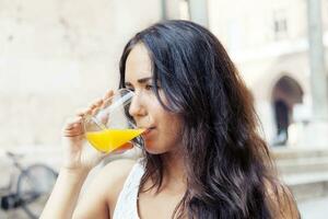 ritratto di attraente ragazza mentre potabile un arancia succo foto