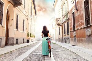 giovane ragazza giri con il bicicletta su il strade di un storico città foto