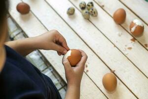 6 anni vecchio bambino pulisce il conchiglia di il Pasqua uova foto
