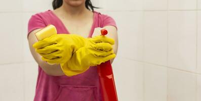 giovane donna attrezzata con spray bottiglia e spugna. faccende domestiche e pulizia concetto. donne preparazione per pulito su bagno foto