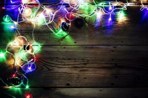 Natale decorativo luci. Natale ghirlanda luci su Di legno. colorato natale leggero bulbi su rustico Marrone tavola foto