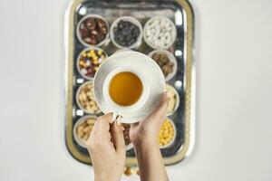 donna mani Tenere un' tazza di tè al di sopra di tradizionale Arabo iftar dolci e spuntini foto