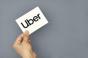 mano detiene un' carta con uber logo foto