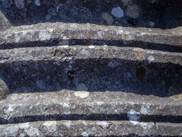 antico lavorato pietra con lichene in crescita su esso foto