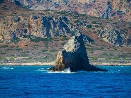 bellissimo montagna e roccioso costa con grande roccia formazione In arrivo su di acqua foto