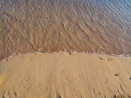 mare onda cancellando il impronte nel il sabbia foto