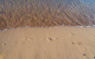 impronte su un' vuoto sabbioso spiaggia - piccolo onde si avvicina foto