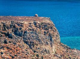 antico torre di guardia in cima il roccioso collina, circondato di in profondità blu mare foto