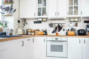 arredamento di il bianca classico cucina con zucche per Halloween e raccolto. autunno umore nel il casa interno, moderno soffitta stile. foto