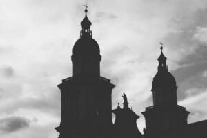 buio silhouette di un antico Cattedrale con Due torri e un' statua nel il mezzo foto