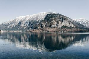 alto montagna coperto con neve riflettendo nel acqua di calma lago foto