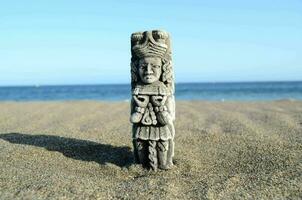 un' lavorato di legno figura su il spiaggia vicino il oceano foto