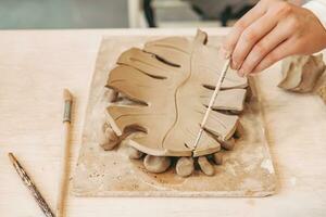 argilla mestiere. fatto a mano. argilla piatto nel il forma di un' mostro. ragazza Lavorando con un' spazzola nel il laboratorio foto